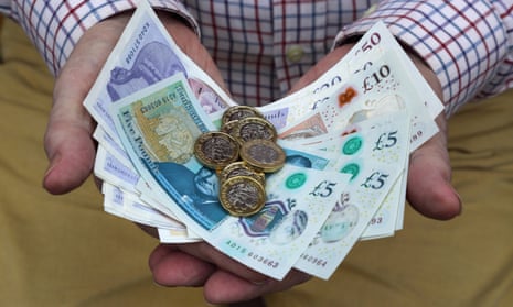 Pound coins and British pound notes in man’s hands