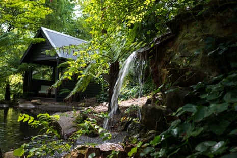 Lush greenery surrounds h2o tumbling down rocks successful beforehand of a building