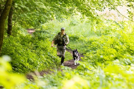 A man runs through a forest with a dog on a lead