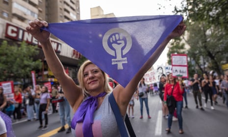 woman holds up bandana with symbol for female, with a fist inside