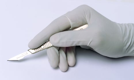 A hand in a surgical glove holding a scalpel