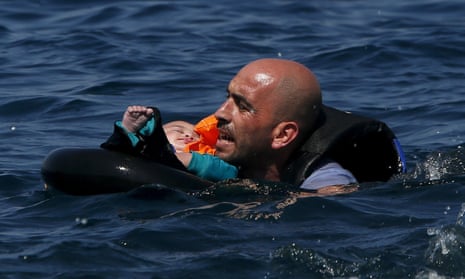 Syrian refugee holding a baby in a lifetube swims towards the shore of Lesbos after their dinghy deflated some 100 metres away.