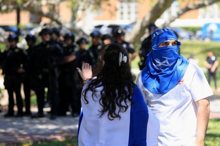 two protesters stand close to a row of police officer