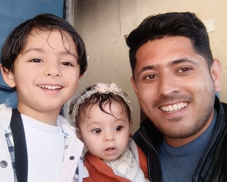 A smiling man with two small children