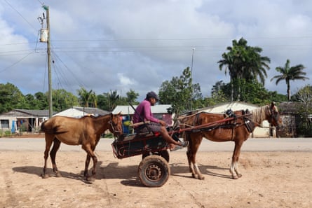 A man sits on a two-wheeled horse-drawn cart with another horse tied behind it