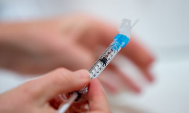 hand holding a syringe of the covid vaccine