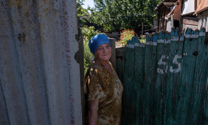 An old woman stands in front of her house in the eastern Ukrainian Donbas region.
