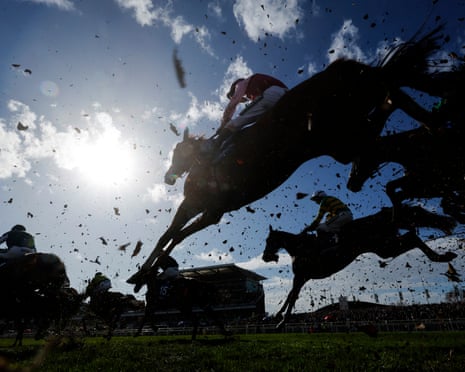 Horses in silhouette jump a fence during the Grand National meeting at Aintree Racecourse