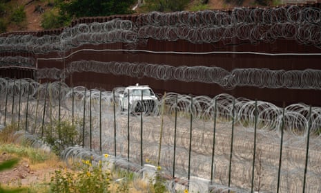 A vehicle drives along the US side of the US-Mexico border wall in Nogales, Arizona.