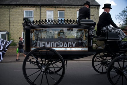 A coffin is carried on a hearse ahead of the anti-migrant march to RAF Barnham, with democracy painted on each side of the box