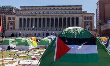 tents in front of a grand building, one with a palestinian flag