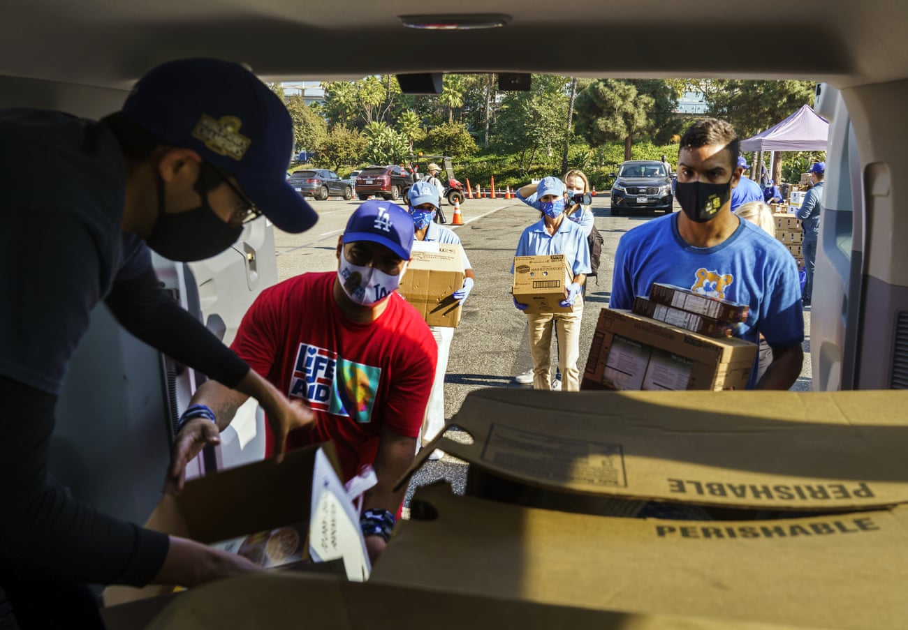 Volunteers help Bresee youth center volunteer, Luis Alarcon, far left, load his foundation’s van with Thanksgiving supplies at a food drive-thru for not-for-profit community organizations at Dodger Stadium parking lot in Los Angeles Thursday, Nov. 19, 2020. 