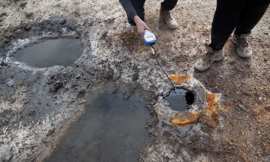 A person takes a measurement from a well.