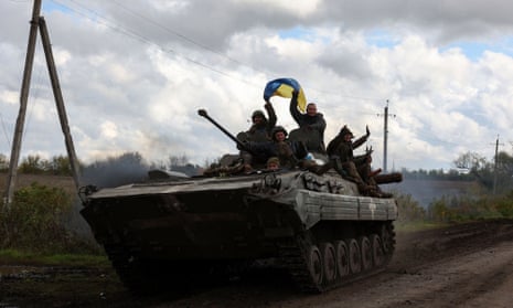 Ukrainian soldiers wave a national flag atop a tank in Lyman