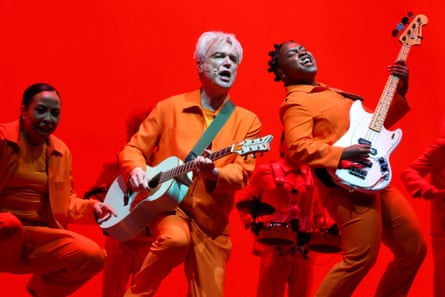 Byrne and fellow musicians on stage in bright orange jackets and trousers