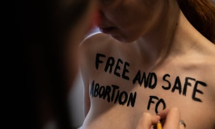 A member of women’s rights group Femen paints the phrase ‘Free and safe abortion for Ukrainian women in Poland’ on the chest of another Femen member, May 2022 in Madrid, Spain