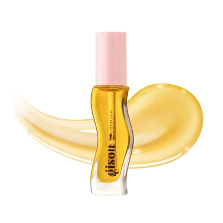 A tube of Gisou Honey Infused Lip Oil. The oil is honey coloured and bottle clear so the wand is visible. There is a pink lid and a smear of oil behind the product.