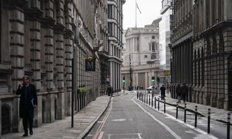 A man talks on the phone while walking in an empty street in London’s financial district.