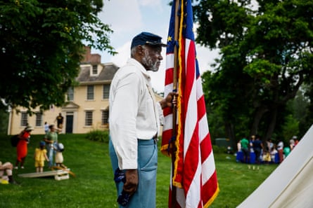 Parties and proclamations: Juneteenth across the diaspora A man pays stands next to the US flag.