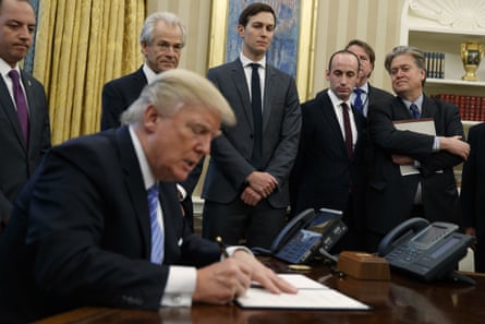 Reince Priebus, Peter Navarro, Jared Kushner, Stephen Miller and Steve Bannon watch as Donald Trump signs the executive orders in the Oval Office, 23 January 2017