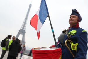 A man wearing a uniform and holding a French flag stands in front of the Eiffel Tower in Paris on March 23, 2019, during an anti-government demonstration called by the ‘Yellow Vest’ (gilets jaunes) movement in Paris.