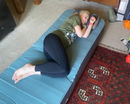 A woman lies on a camping mattress in her living room at home