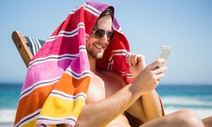 Man looking at his smartphone on a sunny beach