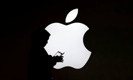 A woman uses a phone in front of an iphone logo