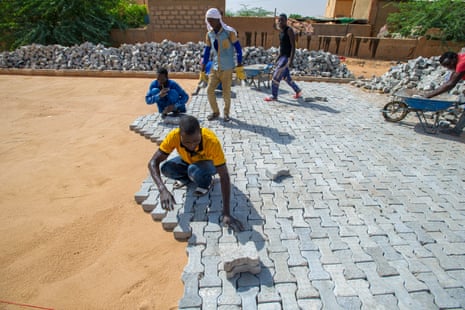 Men pave a road with bricks as part of an EU-funded job scheme in Agadez, Niger