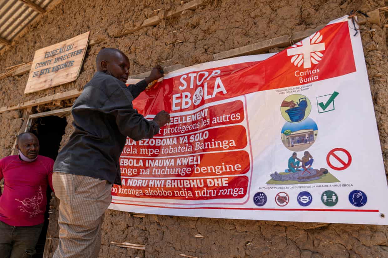 A man hangs an Ebola awareness banner in the Kigonze camp in Bunia.
