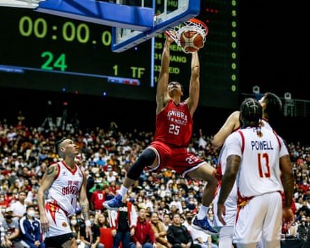 A basketball player doing a slam dunk as opposing players look on