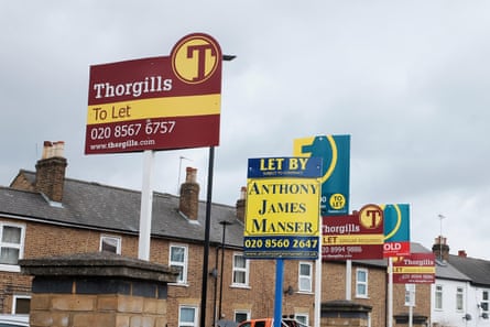 A row of estate agents' signs in front of a row of terrace houses