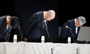 Dentsu president Tadashi Ishii, centre, bows during press conference where he announced his resignation.