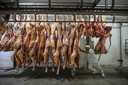 A man in white clothing moves cattle carcasses at a slaughterhouse in Sao Felix do Xingu, Para state, Brazil.