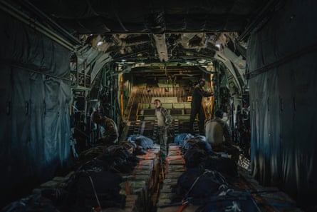 People in military uniform inside a plane with pallets of aid