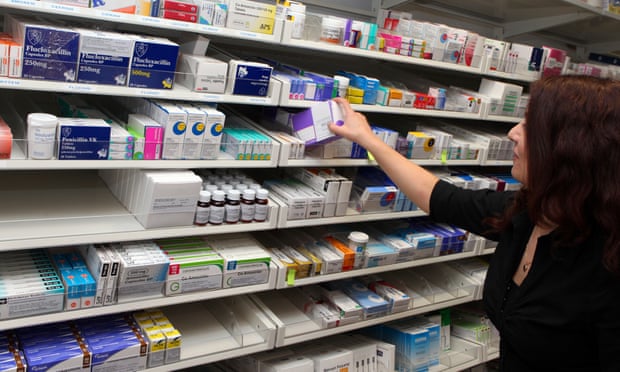 Pharmacy worker takes drugs from shelves.