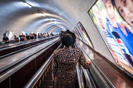 A woman in a leopard-print dress rides an escalator at a Tbilisi metro station