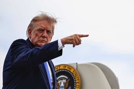 President Donald Trump points his finger while standing in front of the presidential seal