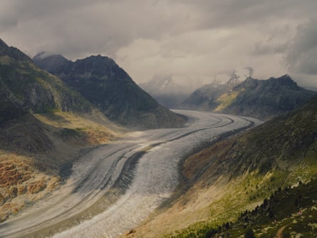 View of a glacier running through a valley with snow-clad peaks in the distance