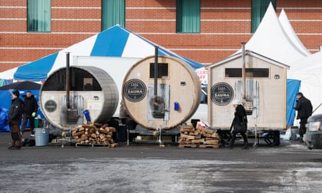 Three portable saunas made from trailers stand in front of a large blue and white tent at a staging ground for truckers protesting Covid-19 restrictions in Ottawa.