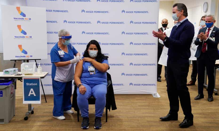 Governor Gavin Newsom applauds ICU nurse Helen Cordova as she receives the coronavirus vaccine.