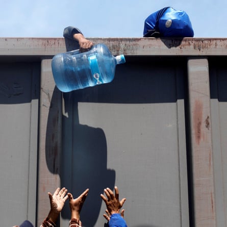 A man assing over container of water as he disembark a freight train in Tlaquepaque, in Jalisco state.