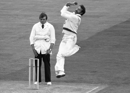 Dickie Bird stands behind the wicket as a bowler leaps in the air during their bowling action
