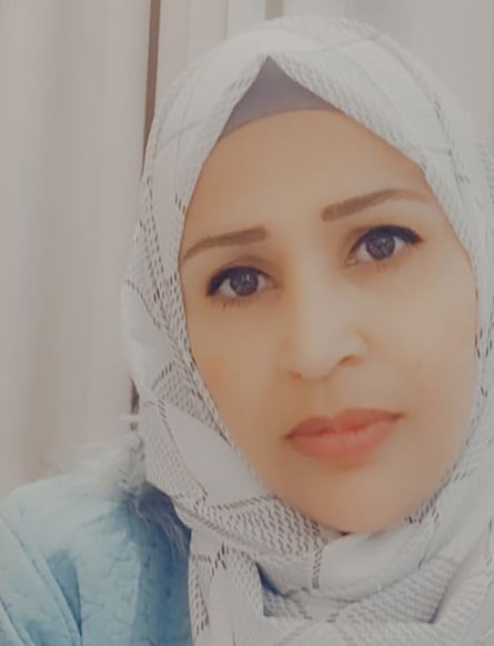A portrait photograph of a woman wearing a white headscarf facing the viewer, white curtains visible behind her.