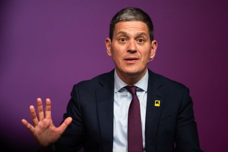 David Miliband gesticulates in a suit against a purple background
