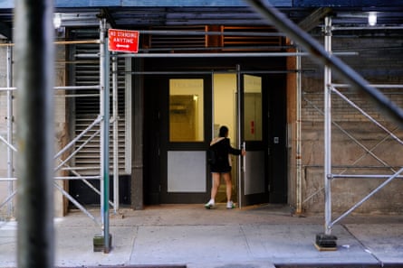 A young woman enters a building with scaffolding around its entrance.