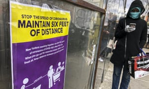 Customers wait outside a supermarket in New York, where signs detail social distancing orders.