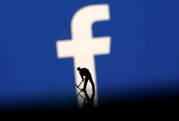 A figurine in front of the Facebook logo