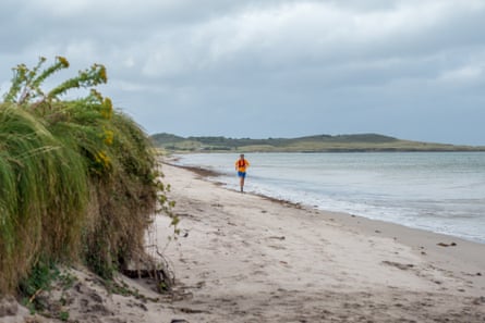 Man runs on sandy beach in dull weather