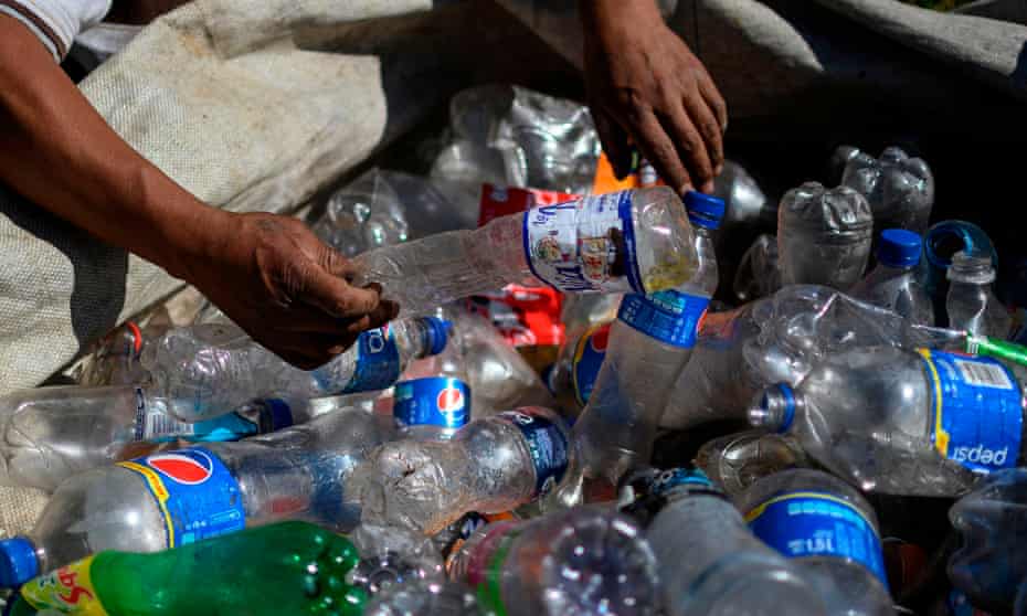 A man sorts empty plastic bottles at a recycling center. 